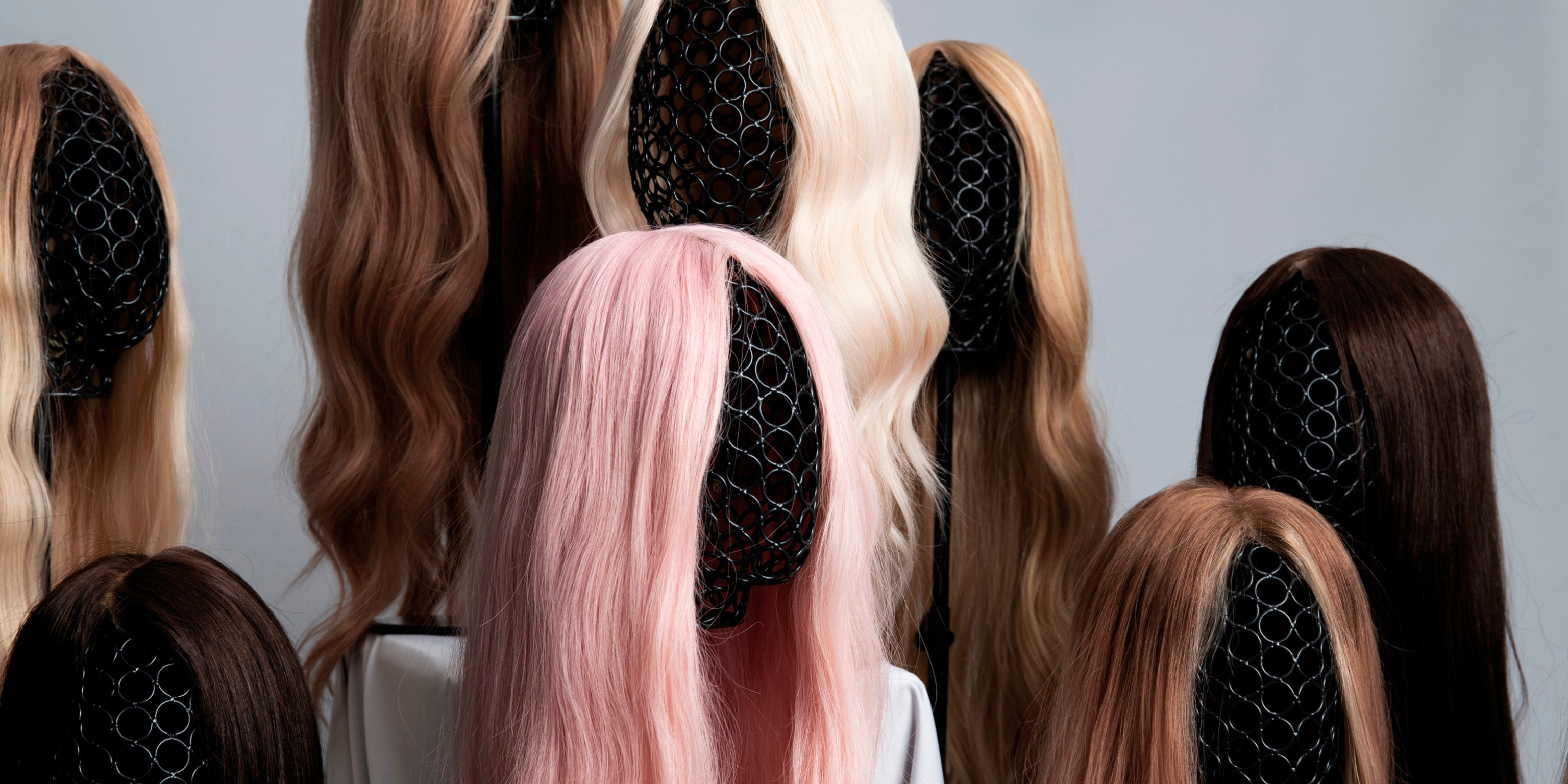 BHBD wigs on wigstands featuring long wigs in blonde, brown and one pink option. 