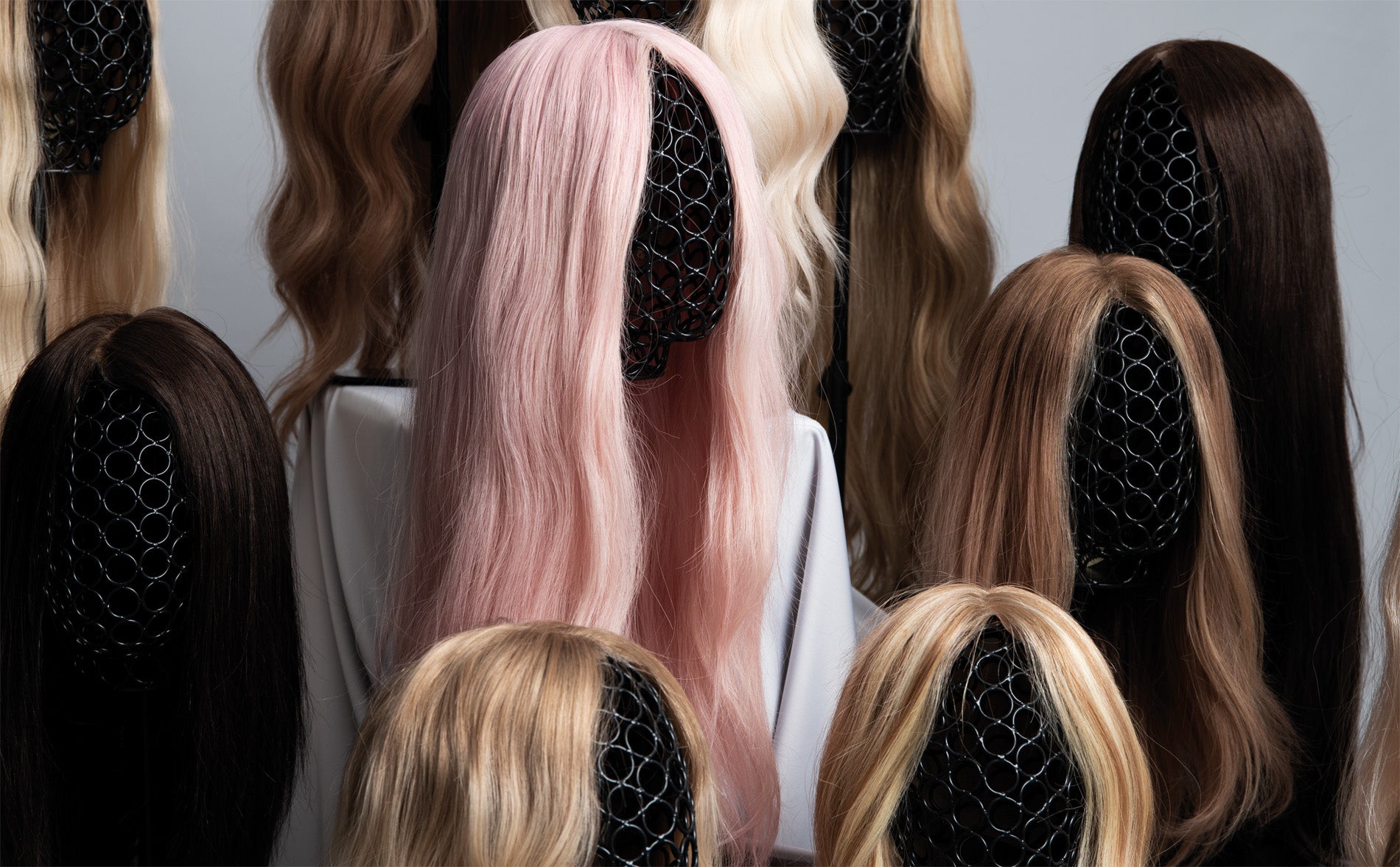 BHBD wigs on wig stands, featuring long styles in blonde, light brown, brown and one pink option.